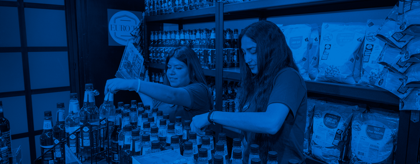 Equipo de Kitchen Experts organizando productos en tienda Eurotea. Amplio surtido de jarabes, tés y accesorios para bebidas. Atención profesional y variedad garantizada.