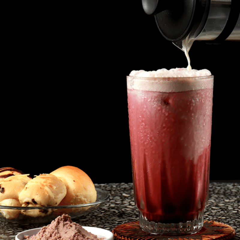 Mocktail Coconut Red Velvet con espuma cremosa y base de coco, servido con hielo y acompañamiento de pan dulce. Bebida sin alcohol ideal para cafés o menú de verano.