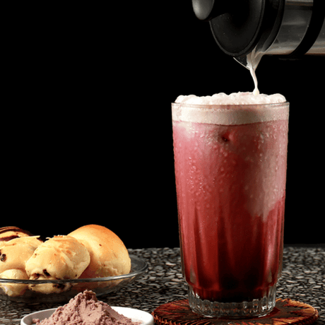Mocktail Coconut Red Velvet con espuma cremosa y base de coco, servido con hielo y acompañamiento de pan dulce. Bebida sin alcohol ideal para cafés o menú de verano.