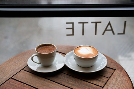 Tazas de espresso y latte sobre mesa de madera: explora los sabores de jarabes para cafeterías y eleva tus bebidas con un toque profesional.