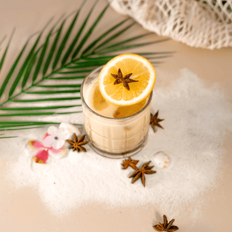 Cóctel frío de especias y cítricos con anís estrella y rodaja de naranja, ideal para bebidas tropicales y mixología creativa.