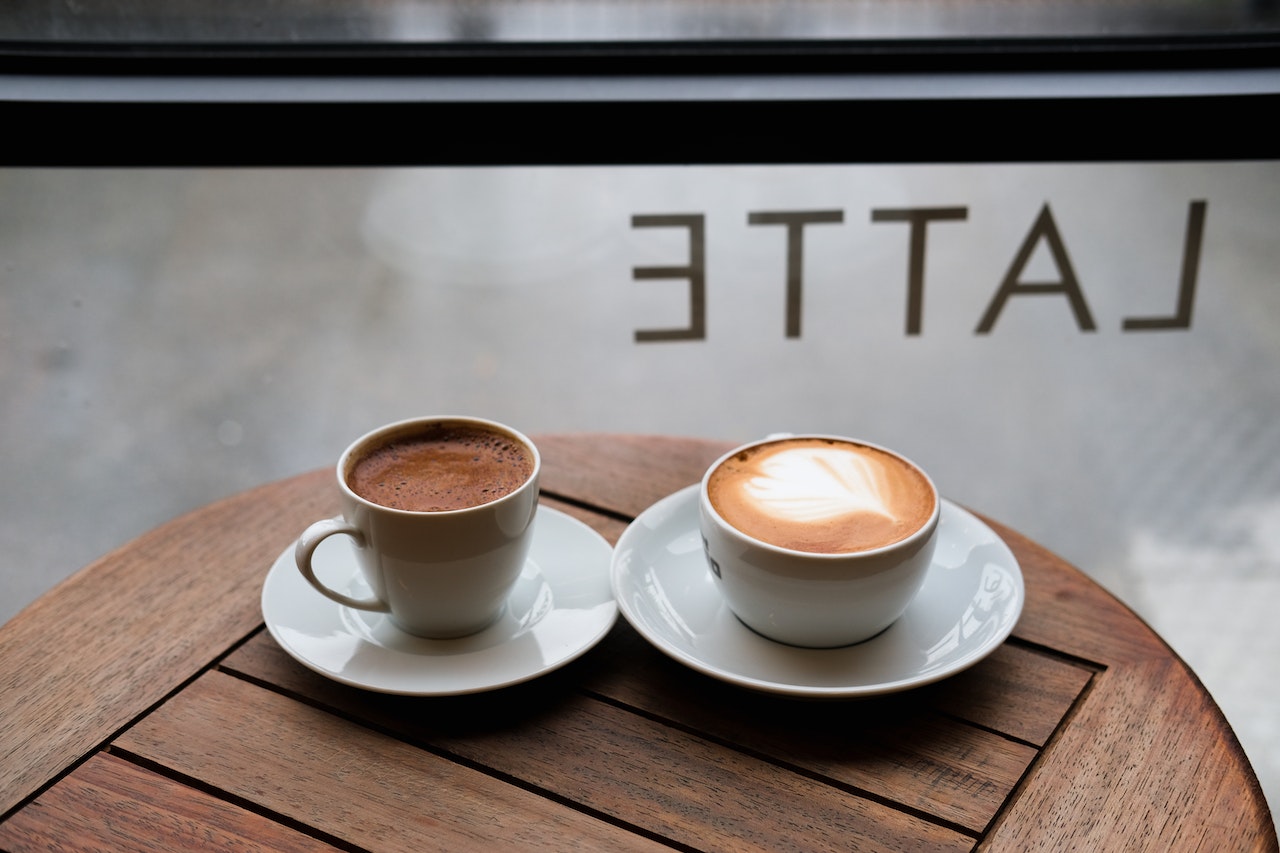 Tazas de espresso y latte sobre mesa de madera: explora los sabores de jarabes para cafeterías y eleva tus bebidas con un toque profesional.