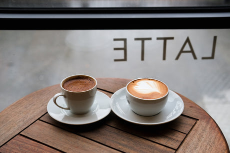 Tazas de espresso y latte sobre mesa de madera: explora los sabores de jarabes para cafeterías y eleva tus bebidas con un toque profesional.