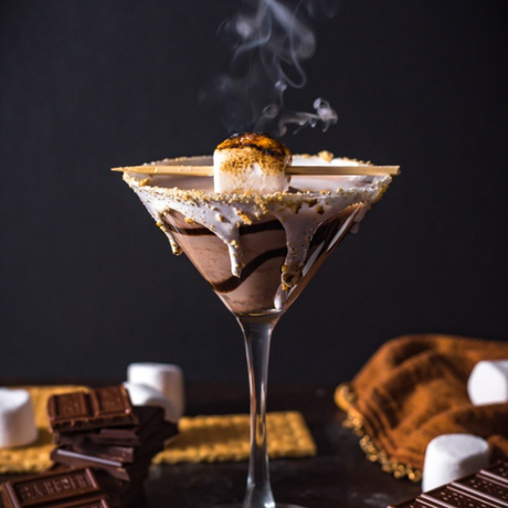 Cóctel estilo martini de s’mores con malvavisco tostado, chocolate derretido y borde de galleta.