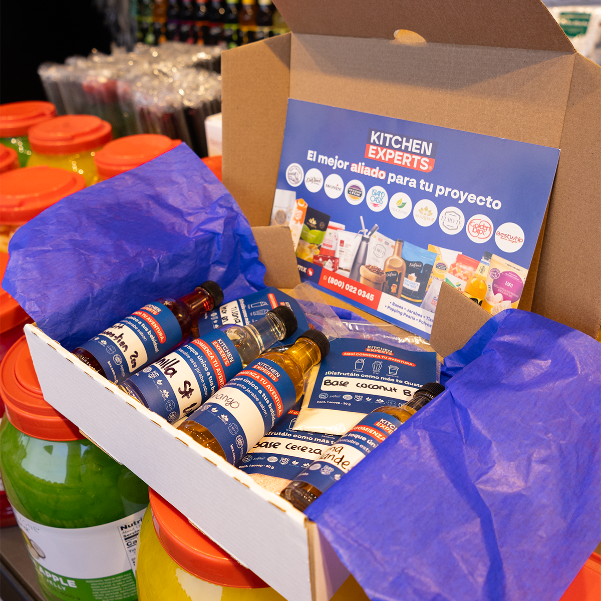 Caja de muestra KEX con jarabes y bases para bebidas sobre mesa de exhibición en tienda – ideal para degustación y prueba de sabores